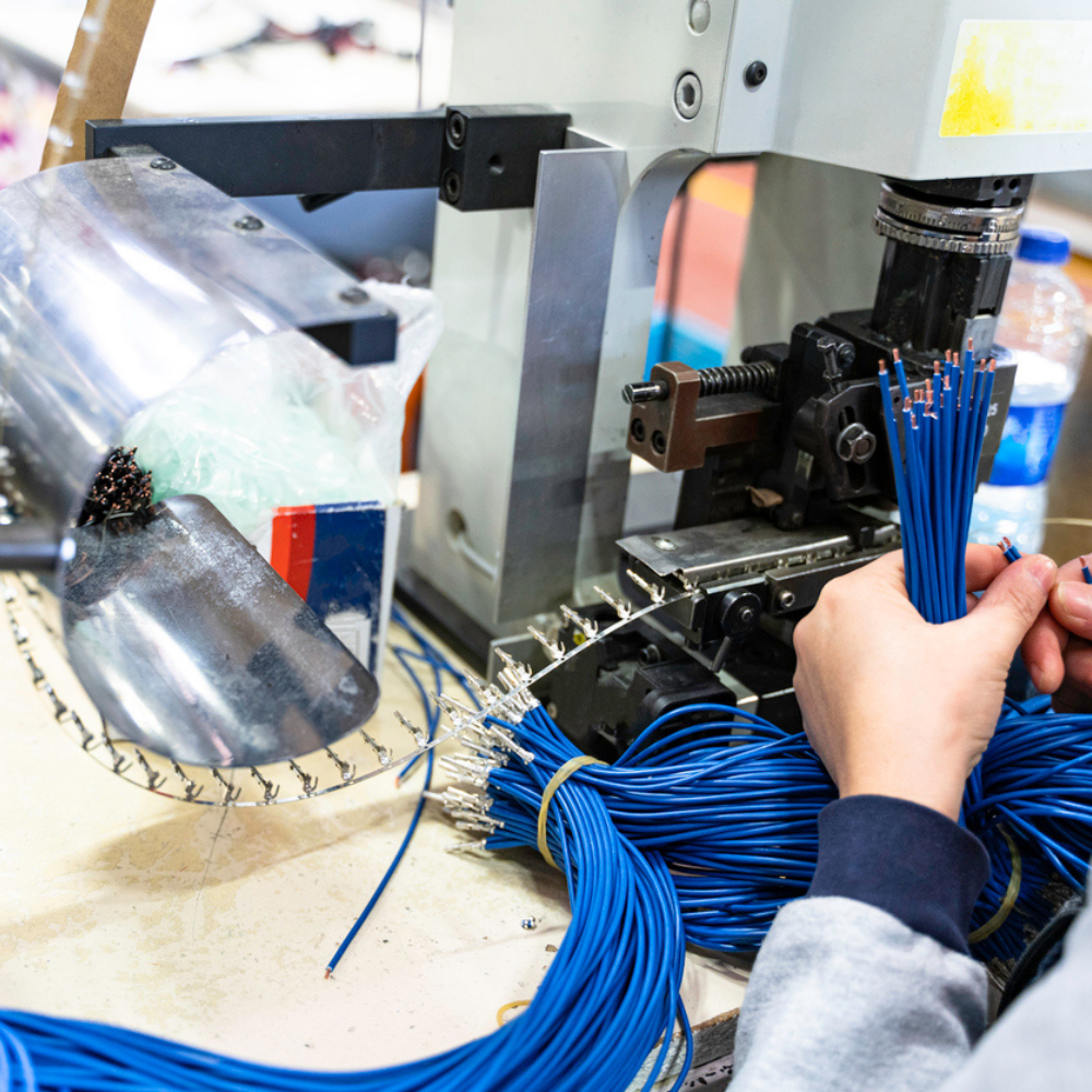 Professional young industrial factory woman employee working with machine parts putting, checking and testing industrial equipments cables in large Electric electronics wire and cable manufacturing plant factory warehouse.