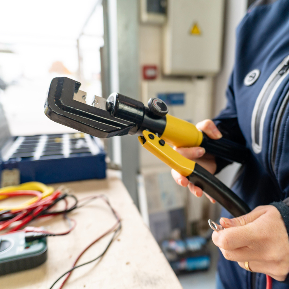 Woman holding crimping tool preparing electrical wires stock photo