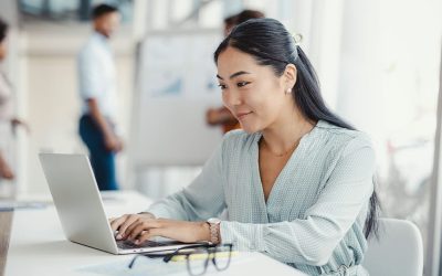 A Person Sitting At A Table Using A Laptop