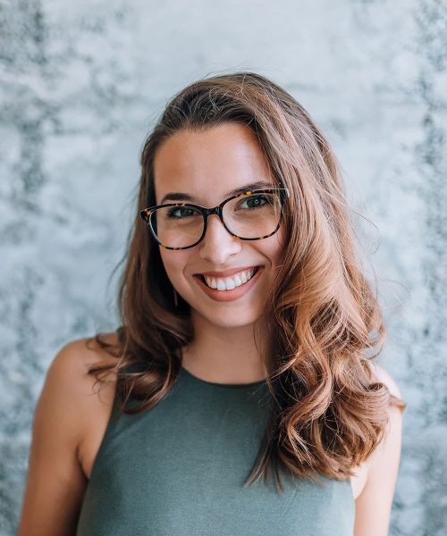 A Woman Wearing Glasses And Smiling At The Camera