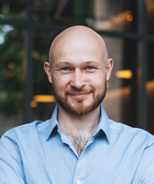 A Man Wearing Glasses And Smiling At The Camera